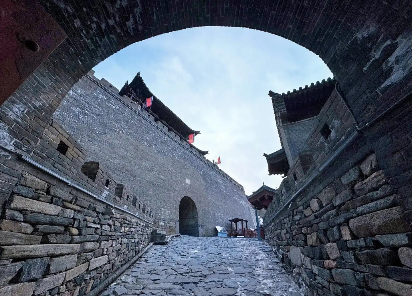 Ancient city wall with traditional Chinese architecture and cobblestone path.