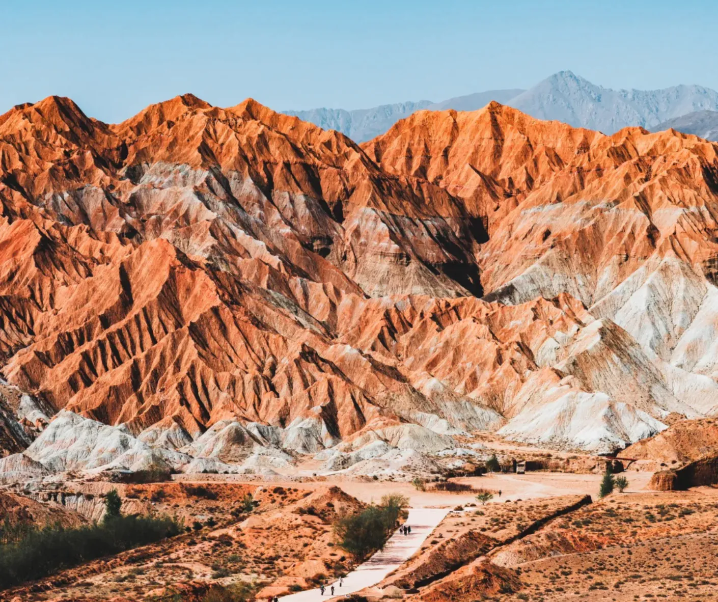 Ridge of orange-red striped mountains with a light path and hikers in the foreground under a blue sky,National Geopark,Hainan Prefecture,Qinghai ,Chinatravel