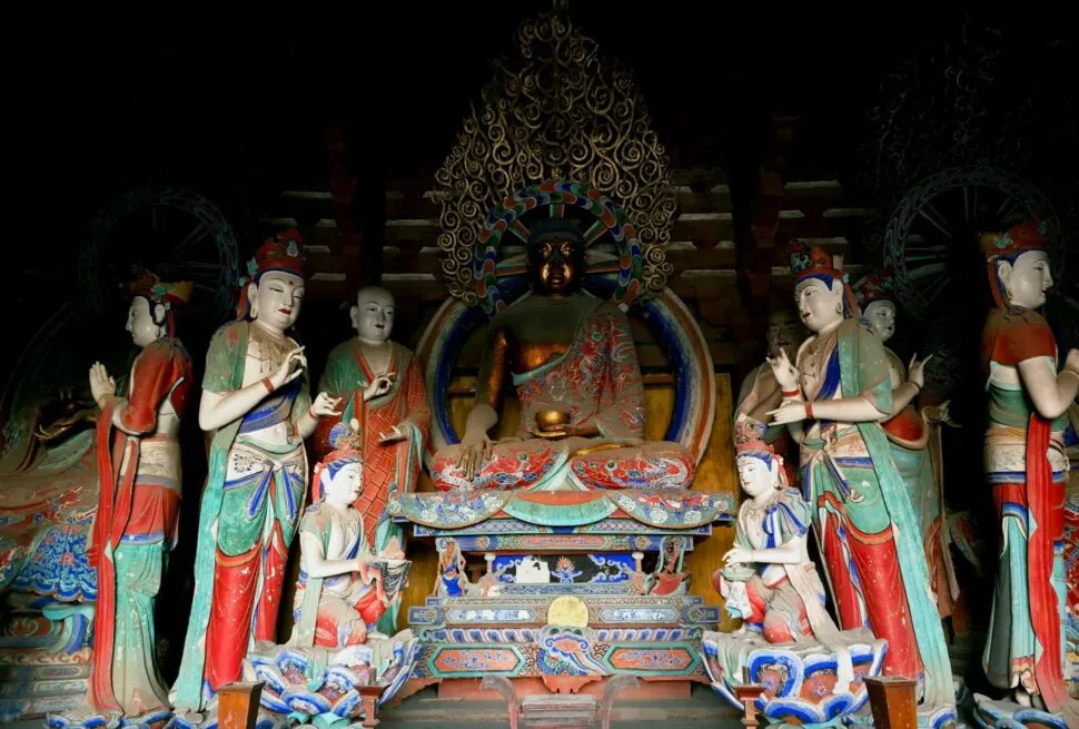Central dark bronze Buddha seated in lotus position, surrounded by colorful standing figures in an ornate shrine,Foguang Temple,Xinzhou,Shanxi