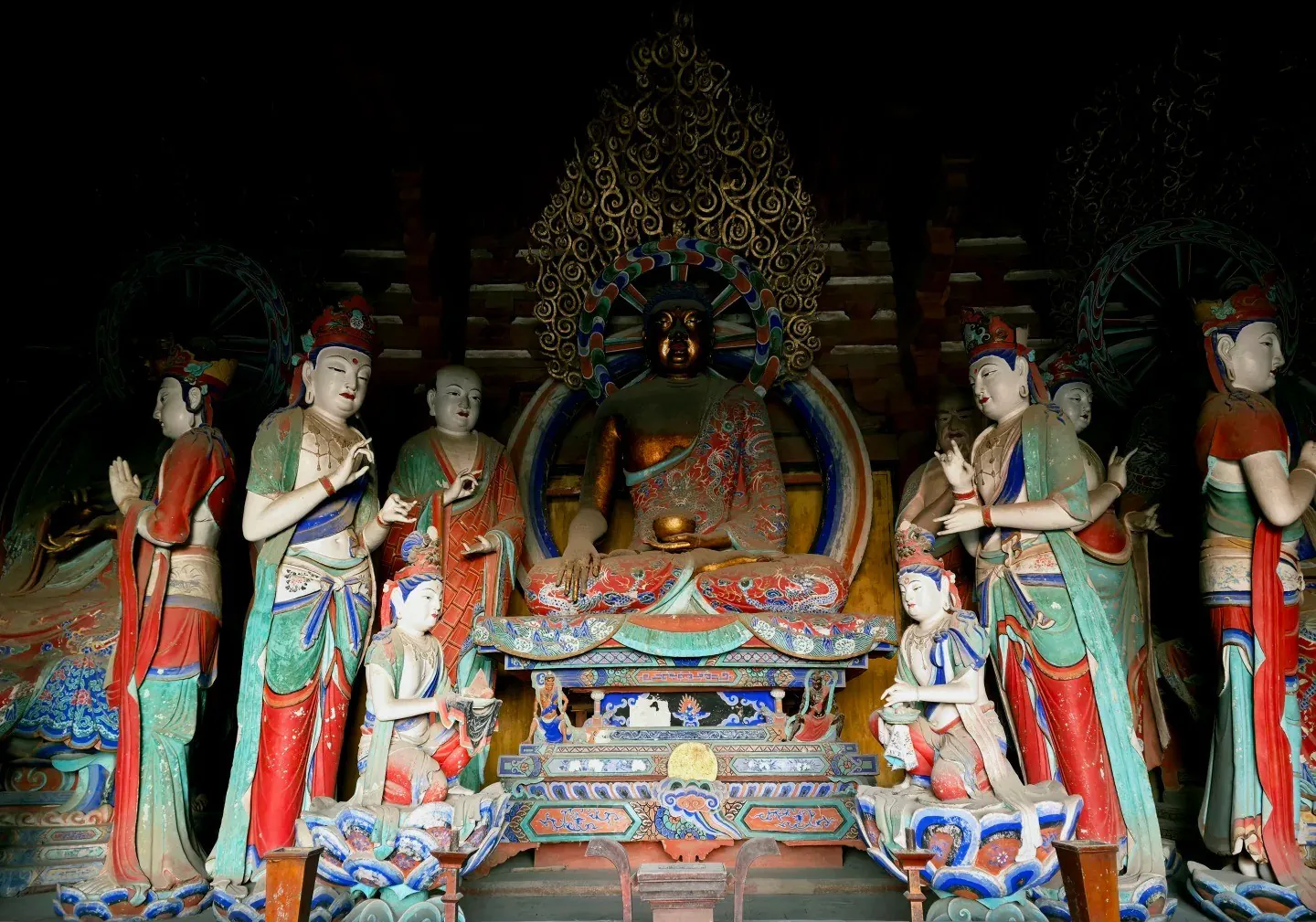 Central dark bronze Buddha seated in lotus position, surrounded by colorful standing figures in an ornate shrine,Foguang Temple,Xinzhou,Shanxi