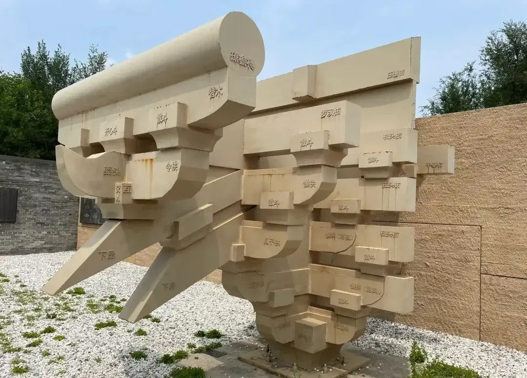 A large beige geometric sculpture with interconnected rectangular blocks.