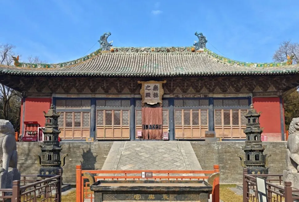 Traditional Chinese temple facade with ornate tiled roof, wooden doors, and stone guardian lions in front.Yongle Palace,Yuncheng,Shanxi