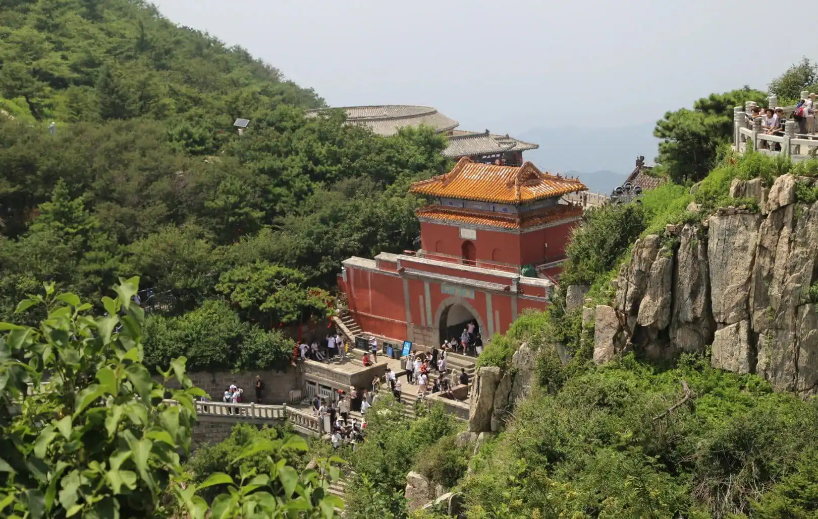 Ancient Chinese temple on Mount Hua surrounded by lush greenery and rocky cliffs.