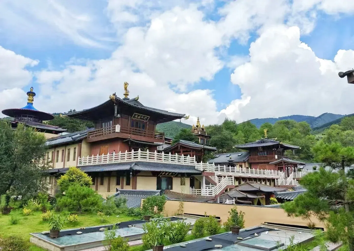 Traditional multi-story temple complex with curved roofs and white railings set in green hills under a blue sky,Ancient Manjushri Temple,Xinzhou,Shanxi