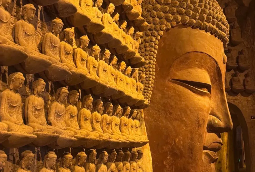 Large Buddha head and numerous small Buddha statues at Longmen Grottoes, China.