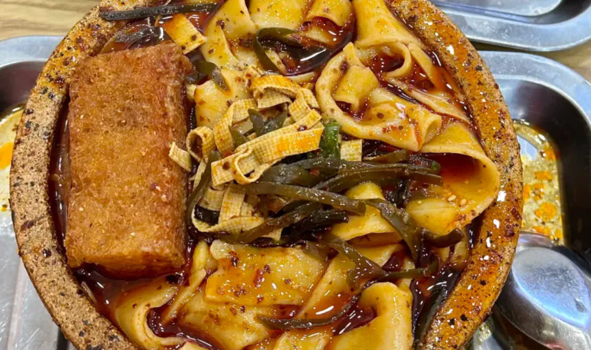 Spicy bowl of Chinese noodle soup with tofu and seaweed, served in a stone bowl.