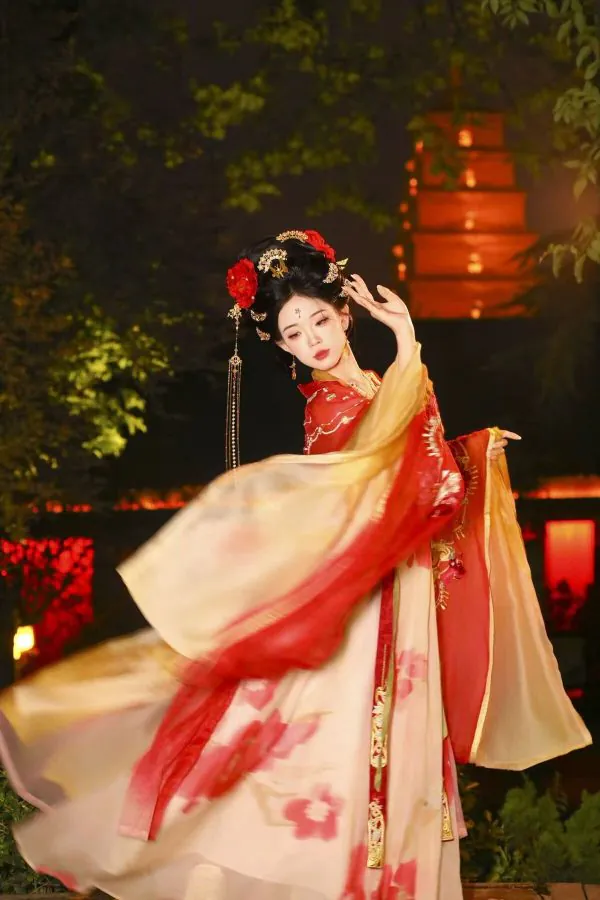 Hanfu photoshoot, xingqing palace, xi'an, solo, tang dynasty, female, chinatravel, A woman in an ornate red and gold hanfu dances with flowing sleeves at night, wearing an elaborate headdress adorned with flowers and ornaments.