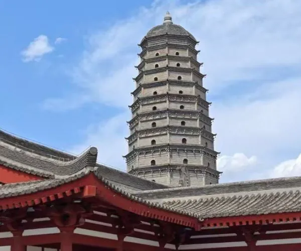 Famen Temple,X`an,Chinatour Seven-story grey pagoda rising behind a red Chinese temple roof under a blue sky.
