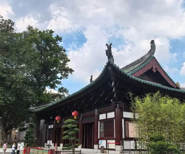 Traditional Chinese temple with a green-tiled, curved roof and red lanterns hanging along the entrance.
