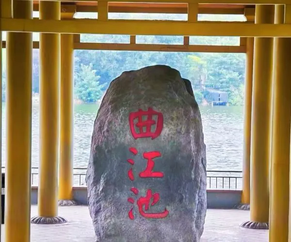 Qujiang Pool Park,Xi`an,Chinatour Rock with red Chinese inscription in a yellow pavilion by a calm lake; large boulder centered with vertical red characters reading 曲江池.