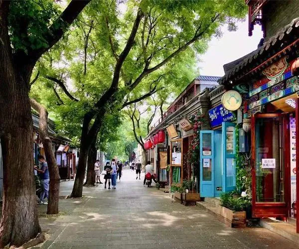 beijing, chinatravel, Pedestrian street lined with colorful shopfronts and a tree canopy, people strolling along the path.
