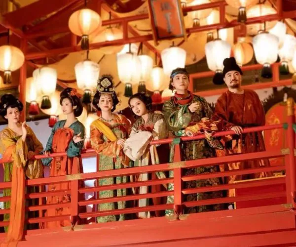 Datang Everbright City,Xi`an,Chinatour Group of people in colorful traditional Chinese costumes standing on a red balcony under hanging lanterns at a festival.