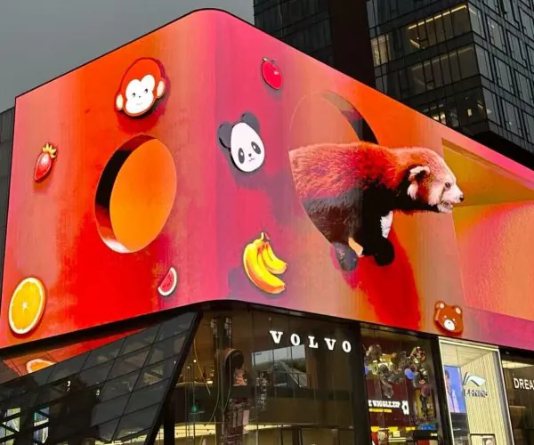 Huge digital billboard above a Volvo store with a bright red–orange background, featuring panda icons, fruit graphics, and a red panda emerging from a curved shape.