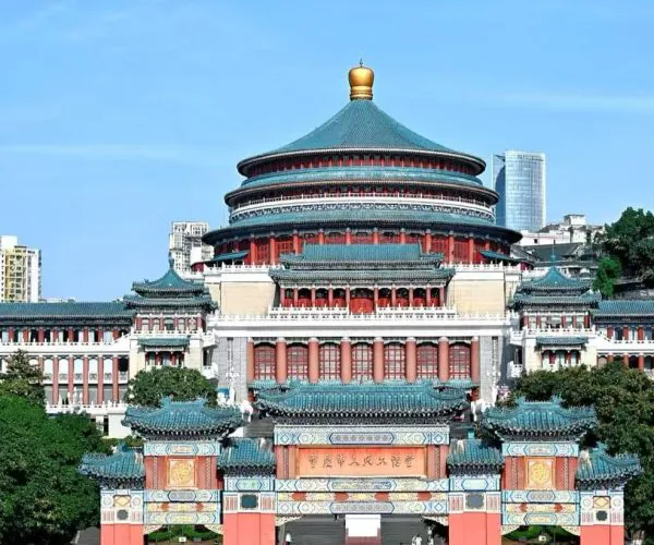 Large Chinese temple complex with a circular, multi-tiered roofed hall and ornate gate in the foreground, flanked by red columns and turquoise tiles against a city skyline.