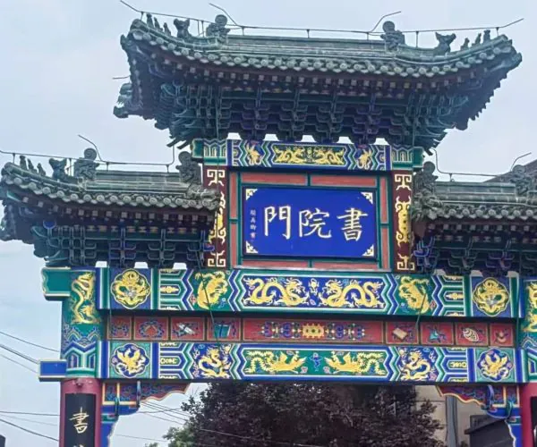 Shuyuanmen Ancient Cultural Street,X`an,Chinatour Colorful traditional Chinese paifang with ornate dragons and blue signboard at the center, in a street setting