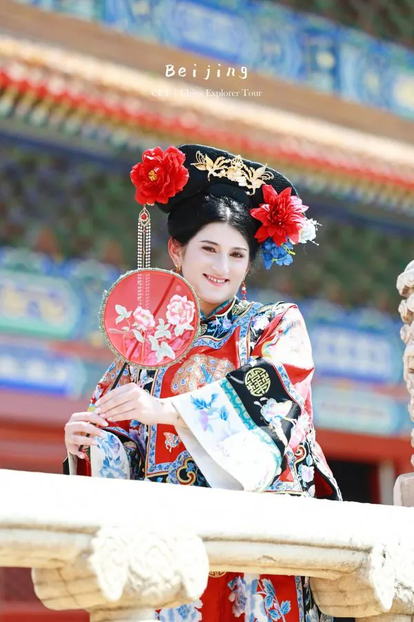 hanfu photoshoot, the forbidden city, beijing, qing dynasty, female, solo, chinatravel, Beijing opera performer in an ornate headdress with red flowers, wearing a colorful embroidered costume, holding a round red fan with pink flowers.