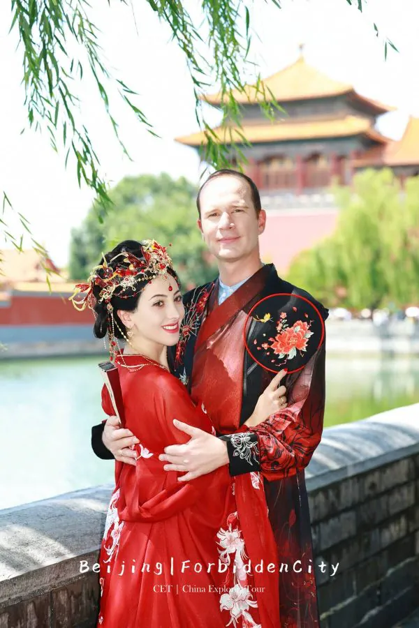 Hanfu photoshoot, the forbidden city, beijing, couple, chinatravel, Couple in red traditional Chinese wedding attire embracing outdoors beside a Chinese palace, with a rooftop temple in the background, and the words Beijing Forbidden City on the image.