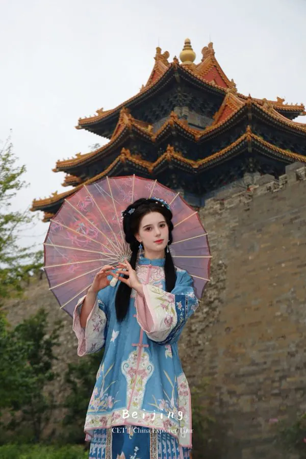 hanfu photoshoot, the forbidden city, beijing, qing dynasty, female, solo, chinatravel, Woman in a blue traditional Chinese dress holding a pink parasol, standing in front of an ornate multi-tiered oriental temple roof.