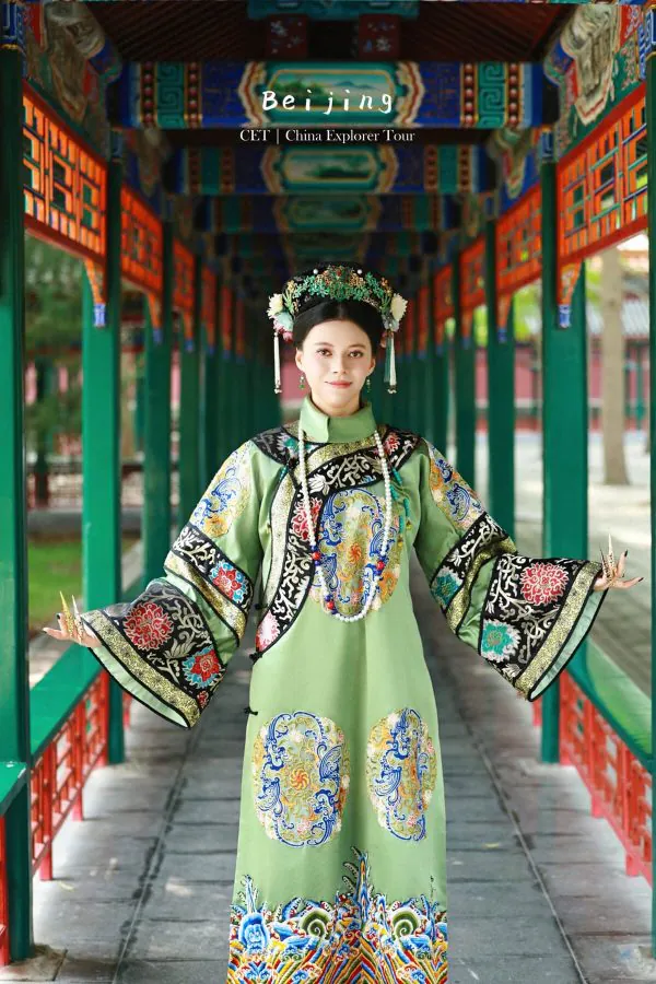 hanfu photoshoot, the forbidden city, beijing, qing dynasty, female, solo, chinatravel, Woman in an ornate green traditional Chinese gown with a jeweled headdress, standing in a colorful temple corridor.