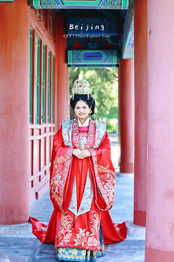 Hanfu photoshoot, zhongshan park, beijing, chinatravel, Woman in an ornate red traditional Chinese imperial dress and gold headdress stands in a red-columned corridor, Beijing tour photo