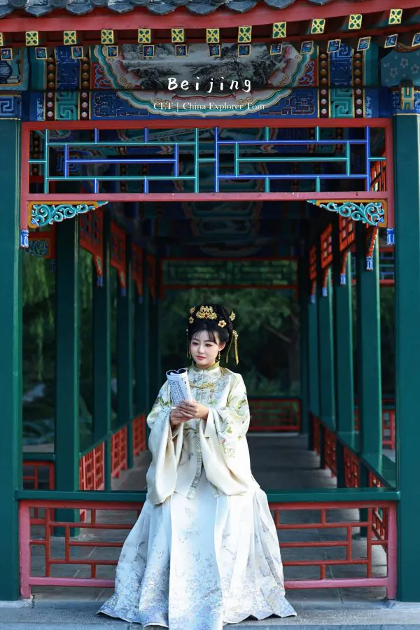 Hanfu photoshoot, the forbidden city, beijing, chinatravel, Woman in a pale blue traditional Chinese gown stands in a colorful Beijing pavilion, holding a scroll.