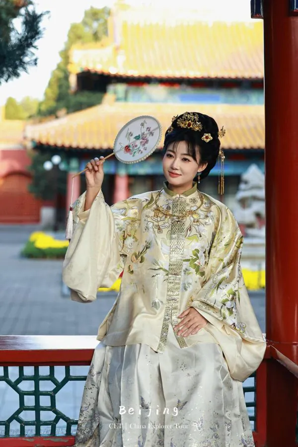 Hanfu photoshoot, the forbidden city, beijing, chinatravel, Woman in an ornate traditional Chinese dress holding a floral embroidered fan, with elaborate hairpins, posing in a Chinese temple courtyard.