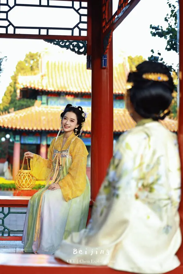 Hanfu photoshoot, the forbidden city, beijing, chinatravel, Smiling woman in yellow and pastel hanfu posing with a woven lantern inside a red-pillar pavilion at a Beijing temple complex.