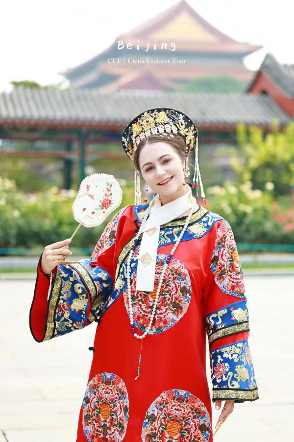 Hanfu photoshoot, zhongshan park, beijing, chinatravel, Person in ornate traditional Chinese dress and headdress, holding a decorative fan, with Beijing-style architecture in the background.