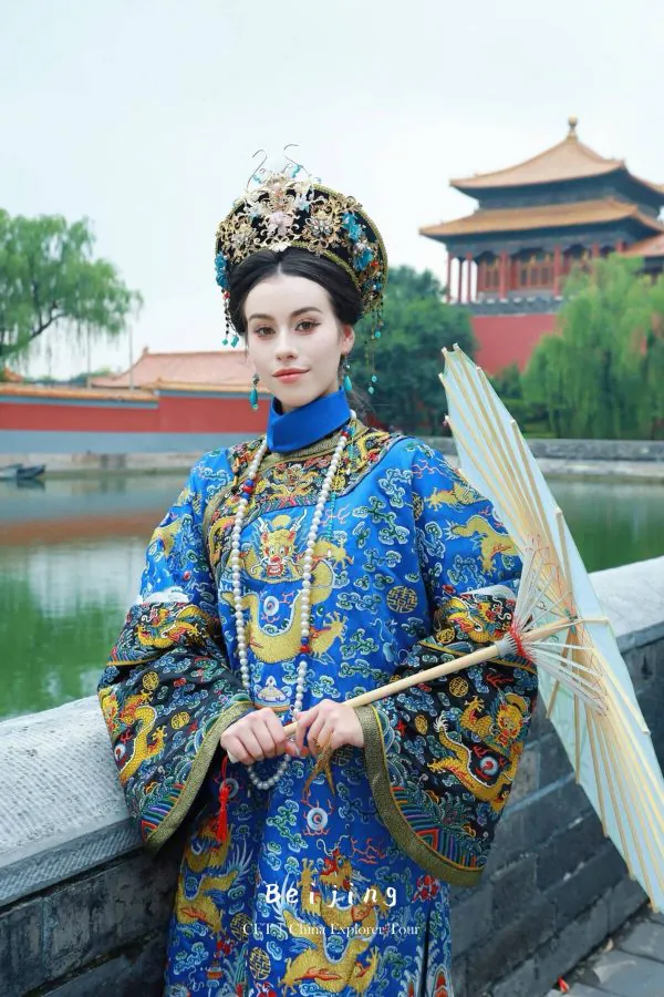 Hanfu photoshoot, zhongshan park, beijing, chinatravel, Young woman in an elaborate blue and gold Chinese imperial costume, jeweled crown, standing by a pond with a parasol.