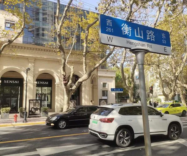 Hengshan Road, Shanghai, chinatrip, Street scene with a blue Hengshan Road street sign in Chinese and English, atop a pole, above a crosswalk and parked cars.