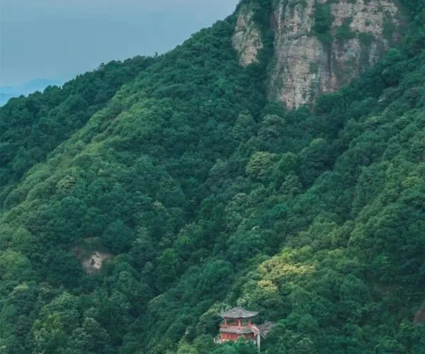 Mount Kuaiji,Shaoxing,Chinatravel Rocky cliff and dense green forest on a mountainside, with a small red pagoda nestled among the trees at the lower slope.