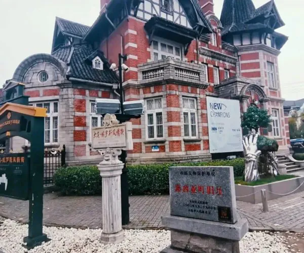Russian Street,Dalian,Chinatravel Historic red-brick building with steep gables and a tower, set behind a pebble-covered garden and signs in Chinese