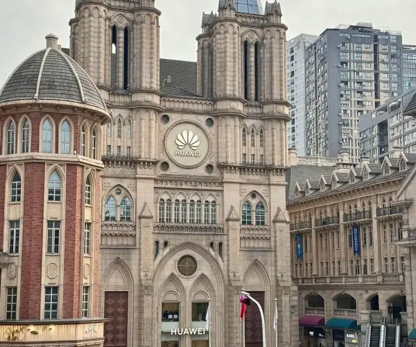 Optics Valley Shopping Center,Wuhan,Chinatravel Historic Gothic-style building with twin spires and a Huawei sign in a city square.