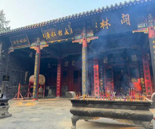 Guanlin Temple,Henan,Chinatravel Traditional Chinese temple entrance with ornate red pillars and golden inscriptions, incense burning in a large bronze brazier in the foreground.