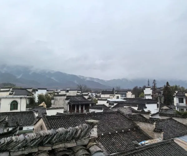Nanping Ancient Town,Huangshan,Chinatravel Traditional cluster of white-walled houses with dark tiled roofs, set against misty mountains on a cloudy day
