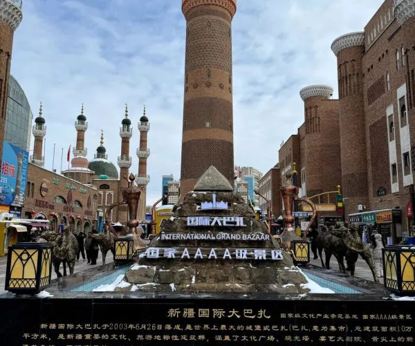 Grand Bazaar,Urumqi,Chinatrip Tall brick minaret towers flank a bazaar complex at the International Grand Bazaar, with a tiered fountain and signs in English and Chinese in the foreground.