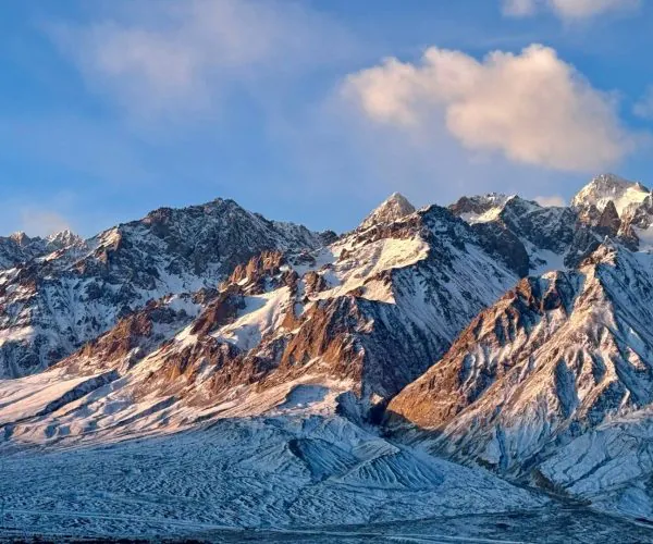 Pamir Plateau (Tashkurgan),Kashgat,China tour Snow-covered jagged mountain range under a blue sky with a few clouds.