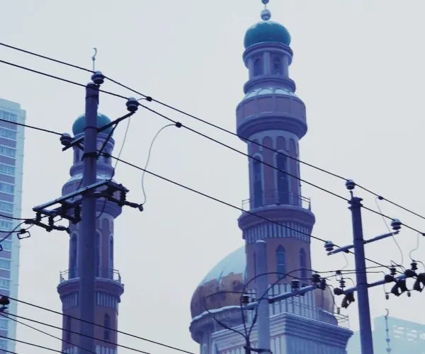 Tartar Mosque,Urumqi,Chinatrip Mosque with turquoise-domed minarets visible behind overhead power lines in an urban setting