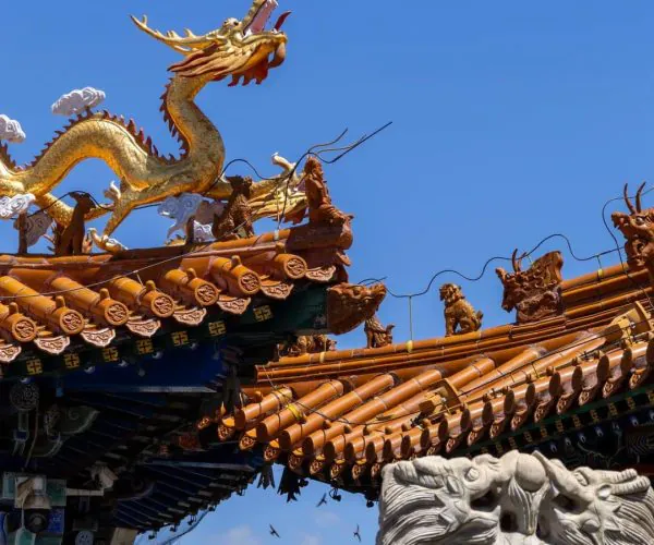 Dazhao Temple,Hohhot,Chinatrip Gold dragon statue atop a traditional Chinese temple roof against a clear blue sky.