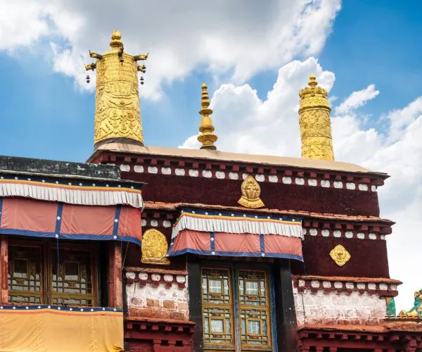 Jokhang Temple,Lhasa,Chinatravel Golden gilded prayer towers atop a red temple façade against a blue sky with white clouds.