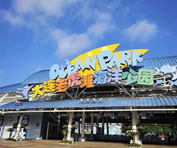 Tiger Beach Ocean Park,Dalian,Chinatravel Entrance to Ocean Park with a large colorful sign and Chinese characters, under a clear blue sky.