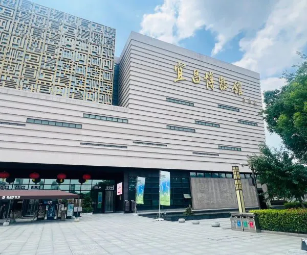 Yichang Museum,Yichang,Chinatravel Exterior view of a modern museum with horizontal beige façade, gold Chinese characters on the wall, and red lanterns at the entrance.
