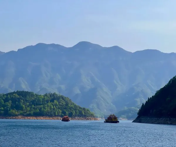 Yichang,Hubei,Chinatour Ancient Chinese boats sailing on a scenic river surrounded by lush green mountains.