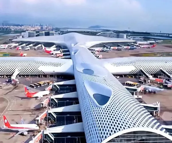 Shenzhen Baoan International Airport,Shenzhen,Transportation Aerial view of a futuristic airport terminal with a dotted white roof and several jet bridges with airplanes parked at gates.