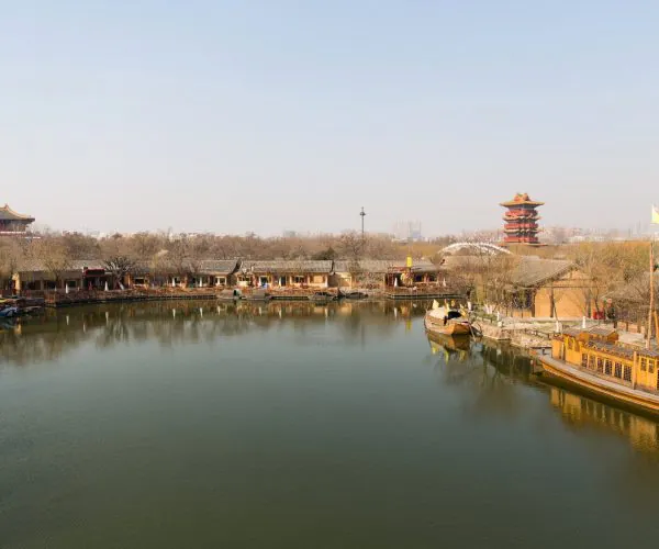 Kaifeng Weather,Kaifeng,Chinatravel Traditional riverside scene with wooden pavilions along a calm lake and a multi-tier pagoda in the distance