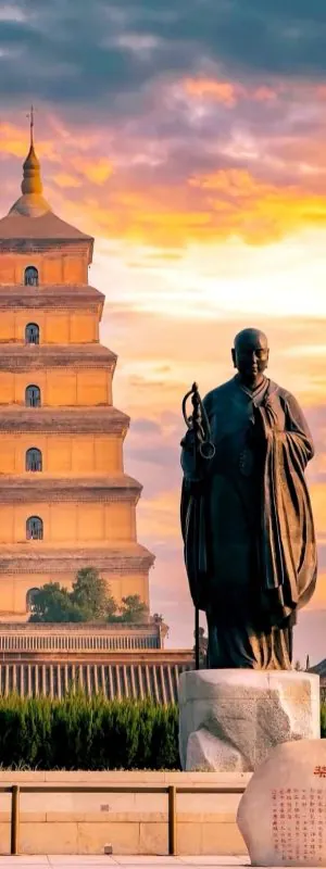 Big wild goose Pagoda, xi'an, shaanxi, chine tour, Statue of a Buddhist monk in robes standing before a seven-tiered pagoda at sunset, with an inscribed rock in the foreground.