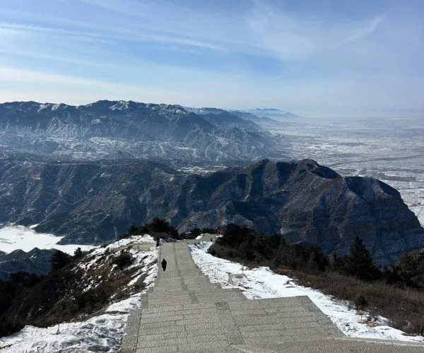 Mount Heng ,Datong,Chinatravel Stone stairway descends a snowy mountainside toward a distant valley and blue sky above.