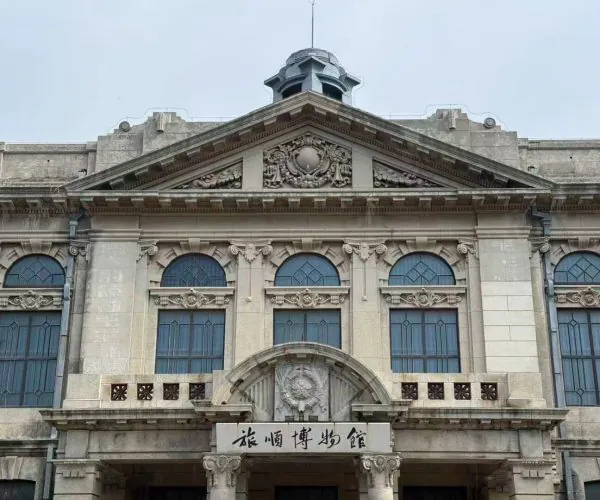 Lushun Historic District,Dalian,Chinatravel Historic stone museum façade with ornate carvings, arched blue windows, and a Chinese sign above the entrance reading 旅順博物館。
