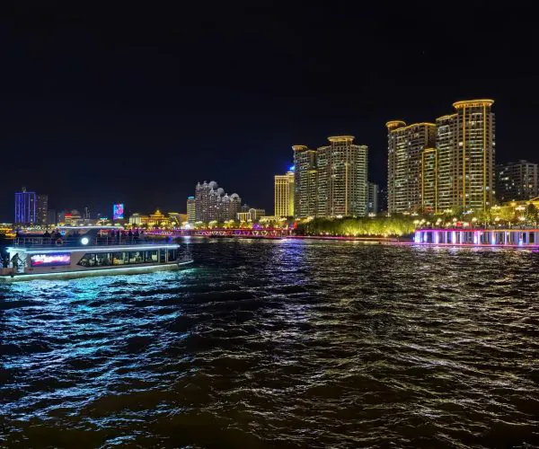 Songhua River,Jilin,Chinatrip Night scene of a illuminated riverside city skyline with a lit boat cruising on dark water.