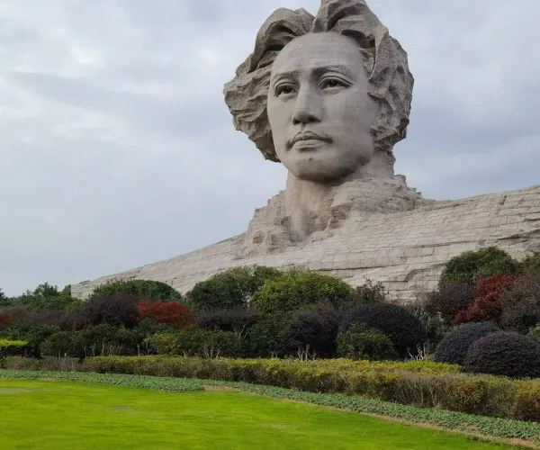 Orange Isle (Juzizhou) Pavilion,Changsha,Chinatravel Massive stone bust of a woman's head rising from a stone pedestal, set in a manicured park with green lawn and shrubs